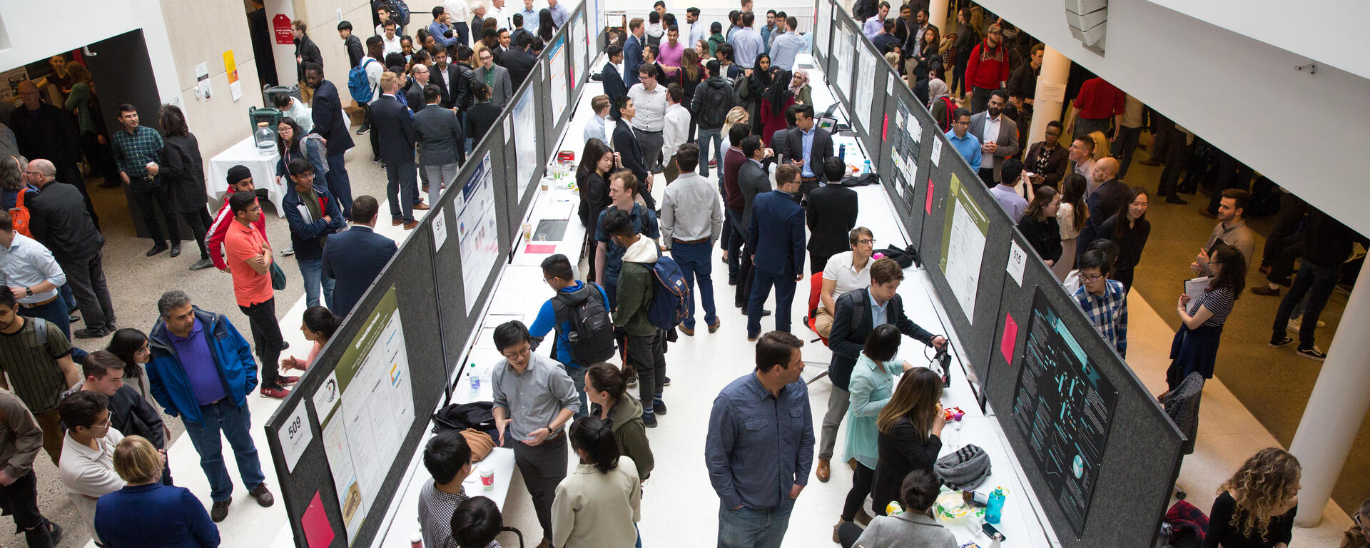 an overhead shot of people looking at student projects set up on tables