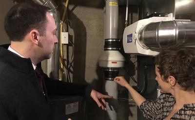 Lindsay Snodgrass shows Aaron Goodarzi the remediation piping and fan unit installed in her home. 