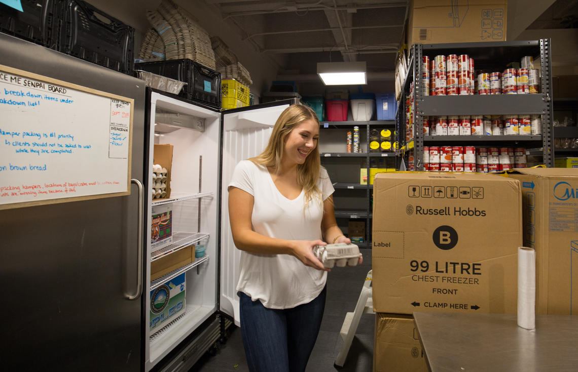 Volunteer Kristen Fequet works with refrigerated goods. The Campus Food Bank has fed more than 10,000 people since 1993.