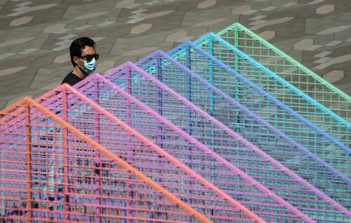 A man wearing a face mask to curb the spread of COVID-19 walks past a temporary Pride art installation in Vancouver on Aug. 3, 2020