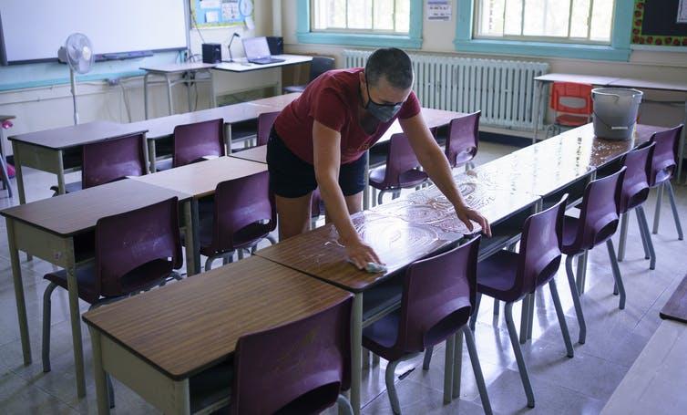 Grade 2 teacher Nancy Poirier washes the desks in her classroom in preparation for the new school year at the Willingdon Elementary School in Montréal on Aug. 26, 2020.