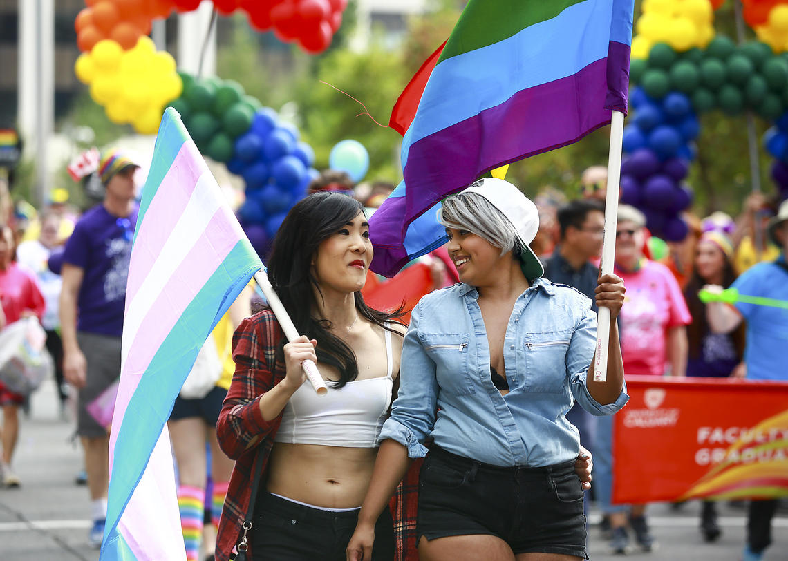 Students with trans flag and pride flag walking together at the 2017 Calgary Pride Parade withUOFCPRIDEPARADE