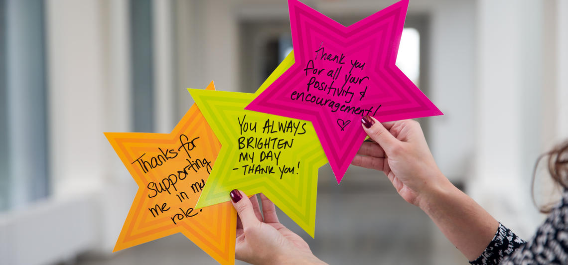 Woman's hands hold up brightly coloured Givin' Thanks stars with positive messages on them. 