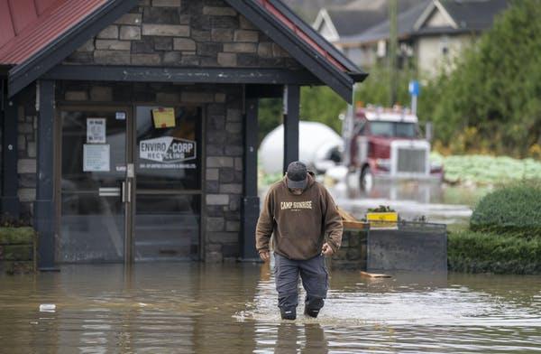 A man walks through rising flood waters crossing into Canada from the United States in Abbotsford, B.C in November 2021. 