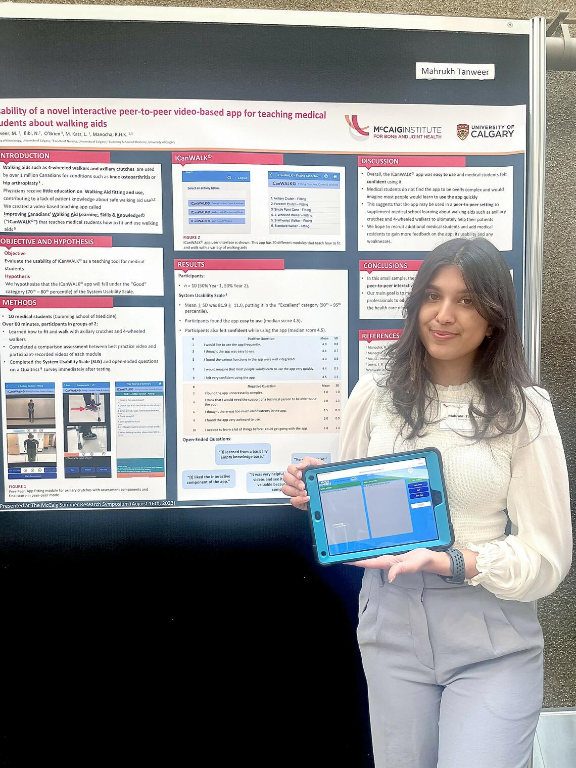 A woman stands in front of a presentation holding a tablet