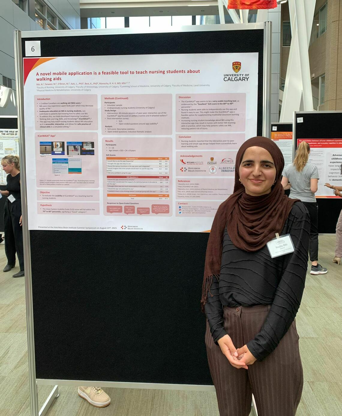 A woman in a hijab stands in front of a presentation board