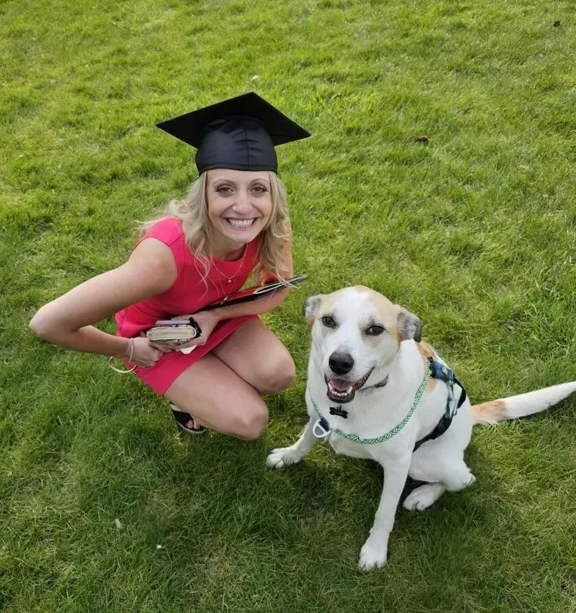 A woman in a graduation cap with her dog