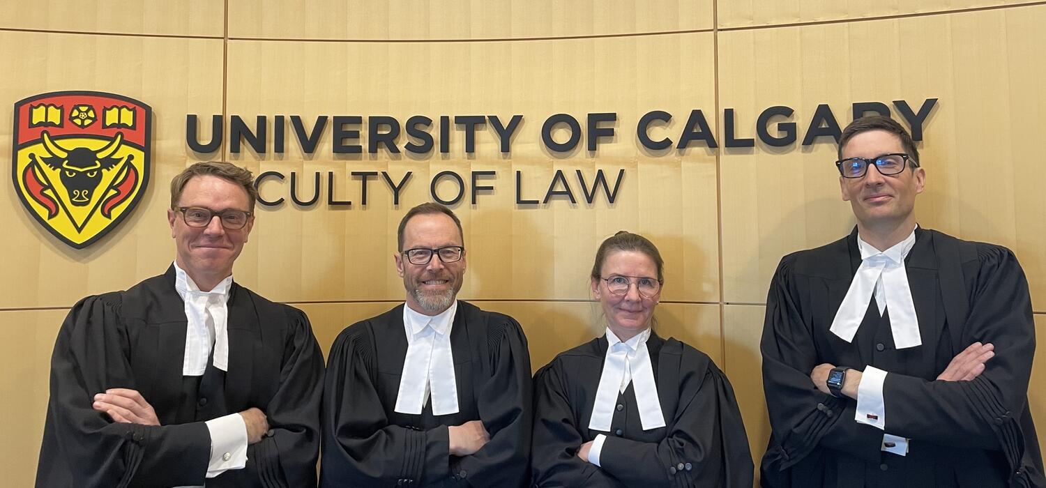 Law professors standing in front of Faculty of Law sign.