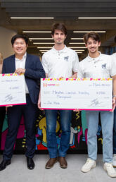 A group of people stand together holding an oversized check