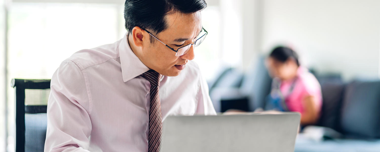 A man in front of a laptop, staring at the papers beside him