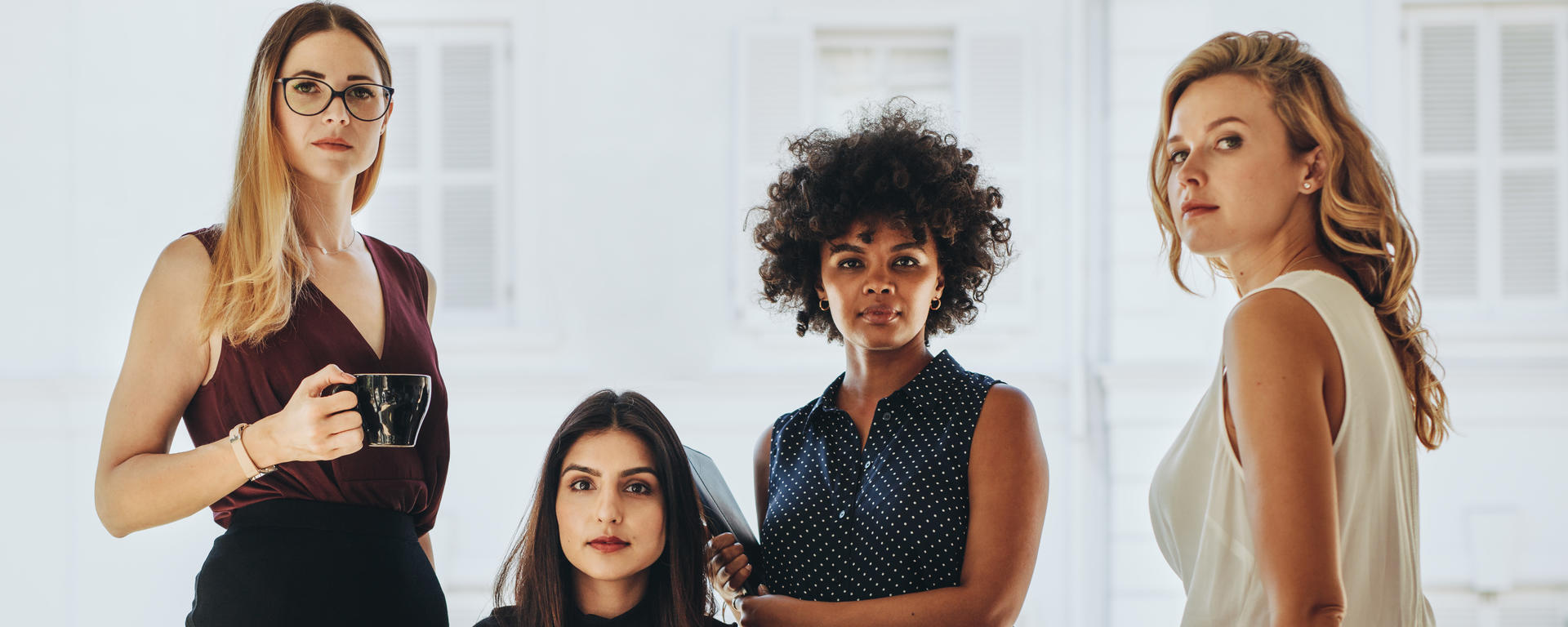 Four business women surrounding a table, looking at the camera