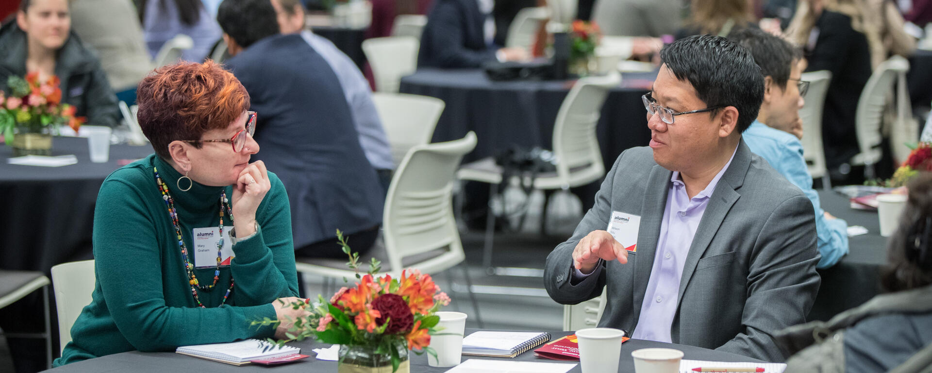 Two individuals sitting at a table chatting 
