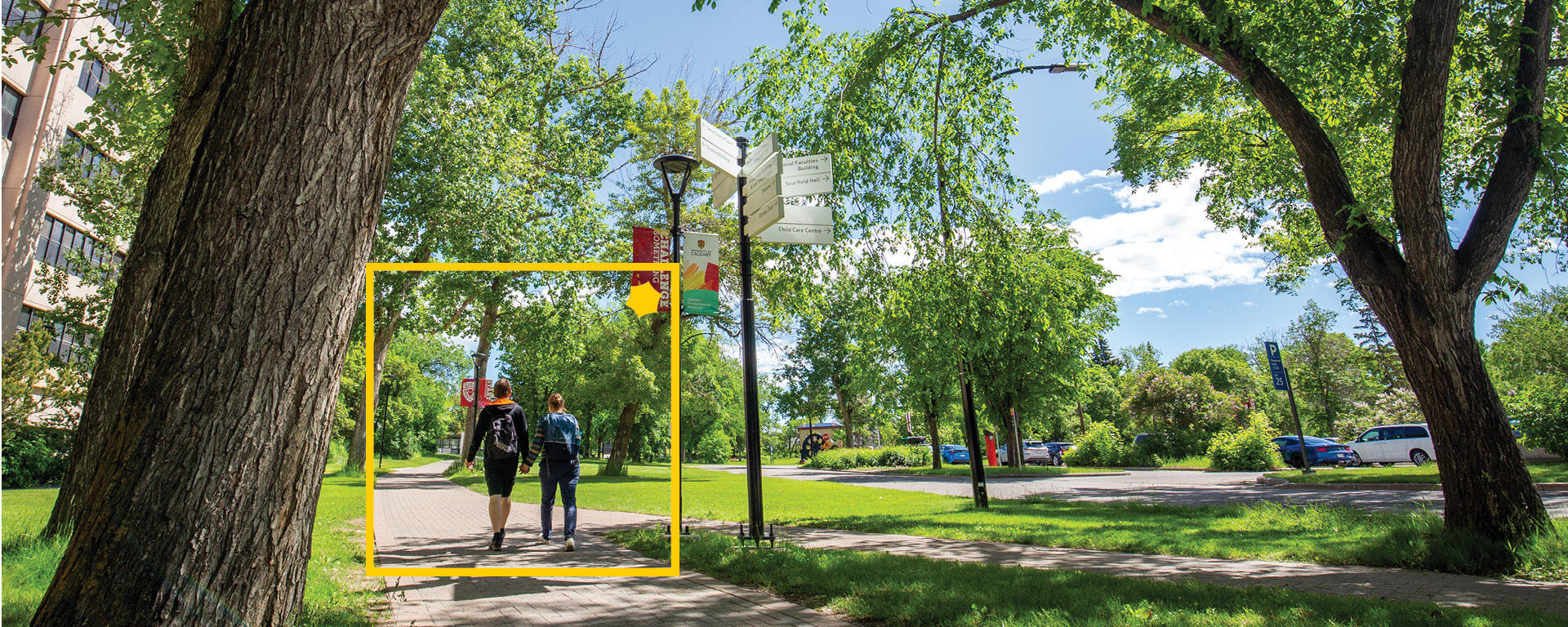 A photo of campus in the summer with a yellow box and Alumni spark around a couple pictured in the photo.