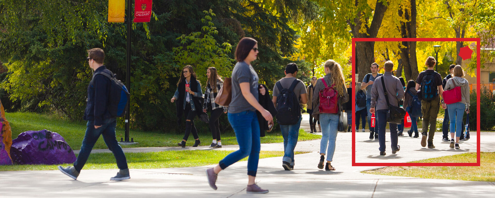 A photo of people milling about campus with the red alumni box around some of them.