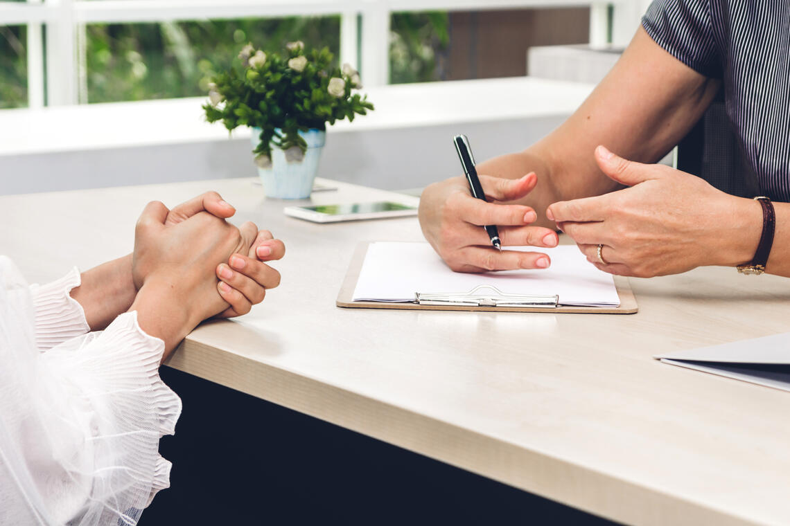 People in conversation with their hands on top of a desk