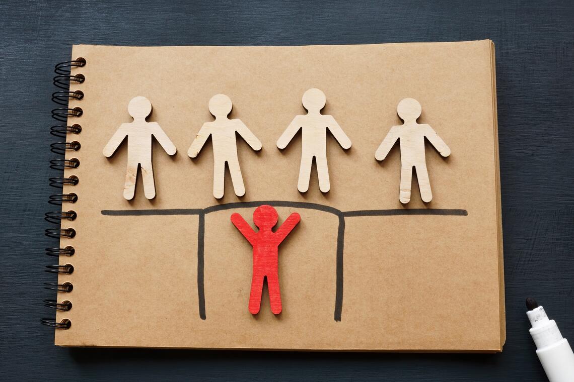 illustration of multiple baige human figures and one red human figure on a page of a collated notebook