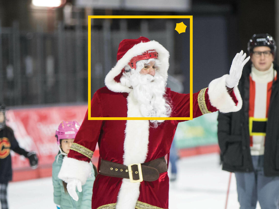 Santa Claus skating with children and adults, with a yellow frame around him that carries the alumni logo symbol.