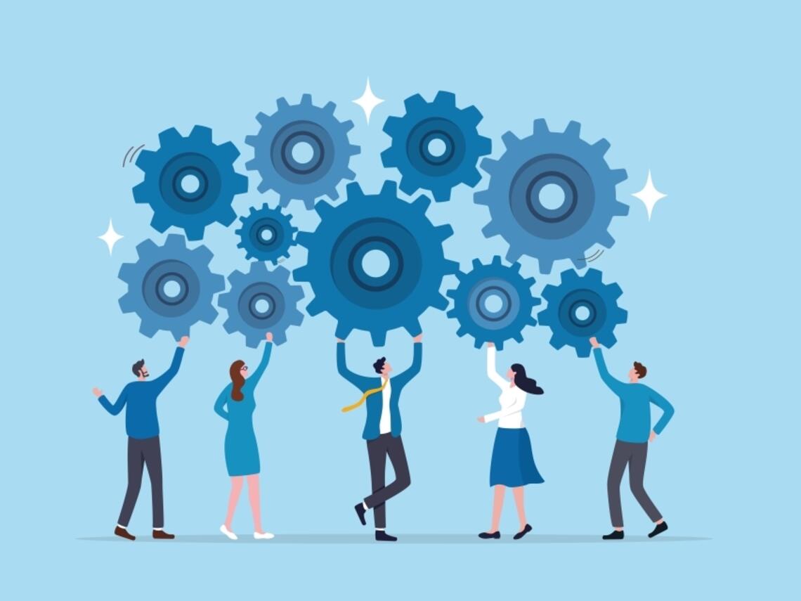 Business professionals collaboratively holding interlocking gears, symbolizing teamwork and cooperation in a corporate setting.