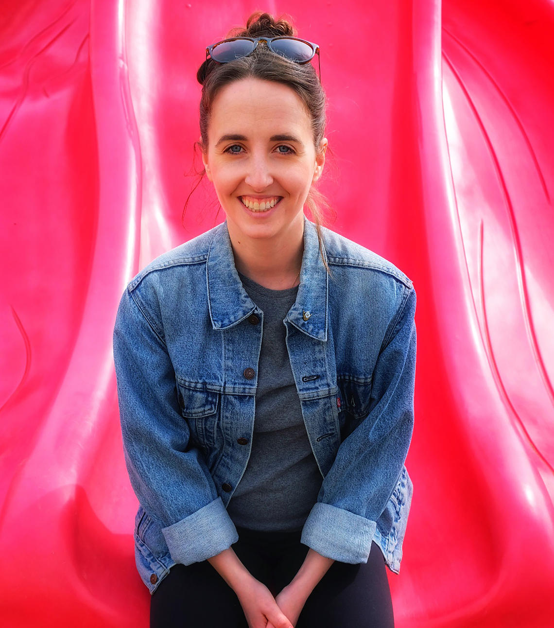 Renata Gordon sits on a red slide in a jean jacket
