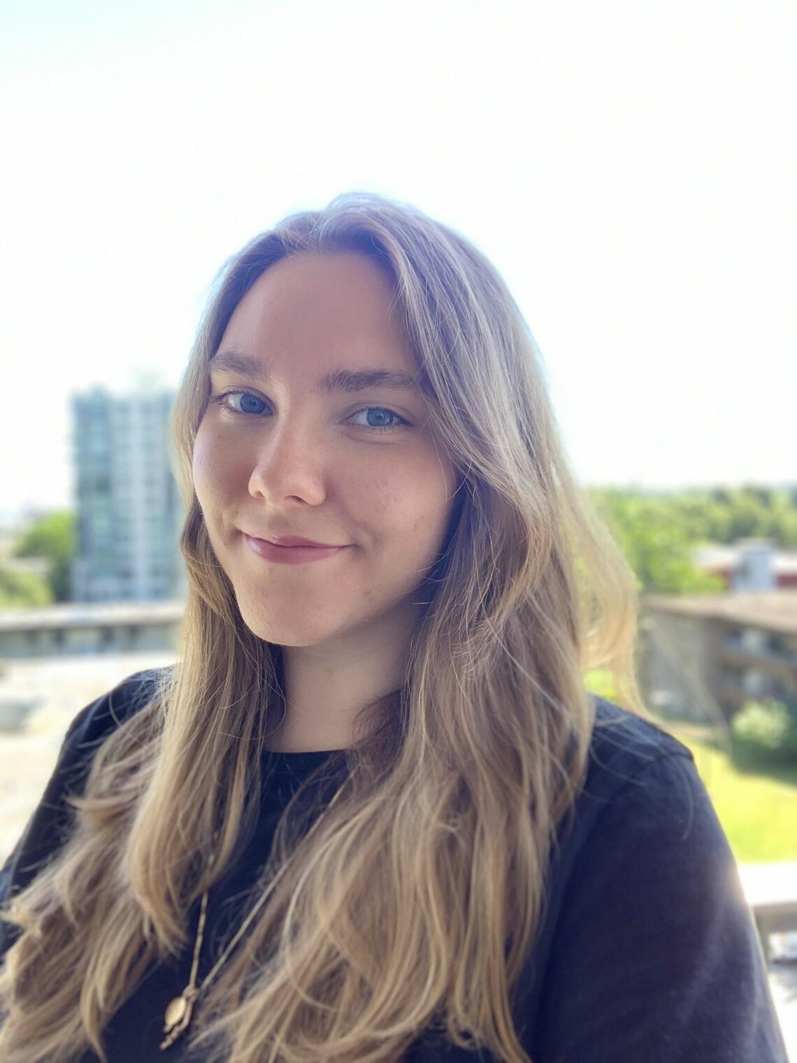 A photo of Mikayla wearing a purple sweater on a balcony.