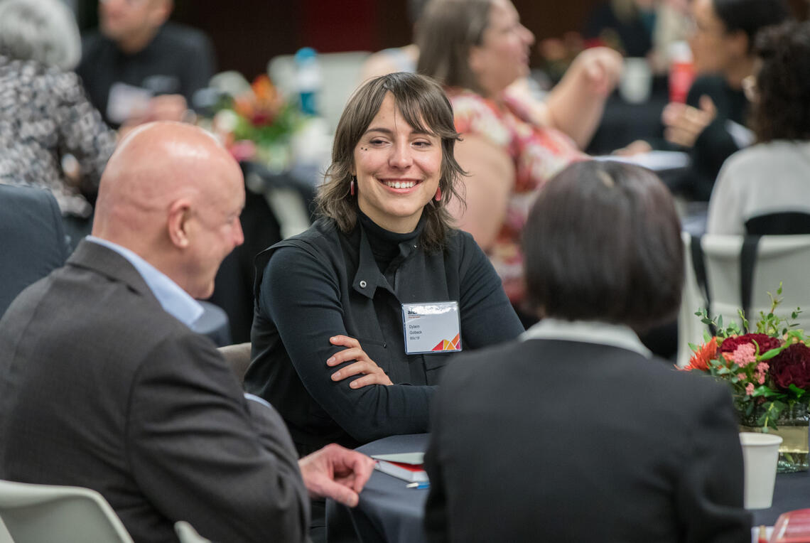 A woman smiles at a table full of participants from last year's Grow Your Career Conference