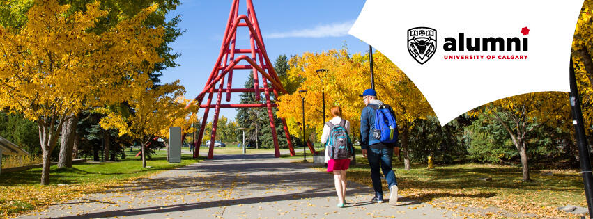 Two students walk under autumn trees toward the red sculpture on the University of Calgary campus.