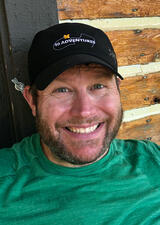a photograph of Richard Campbell wearing a green shirt and a black cap
