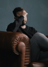 Man sitting on couch with hand on head