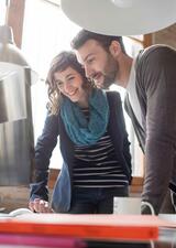 A man and woman smile at a computer screen