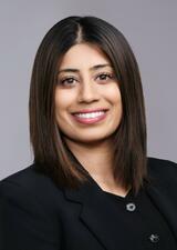 A photo of Nina wearing a black button up in front of a grey background