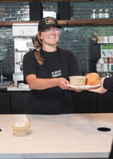 A photo of a woman serving food behind a counter