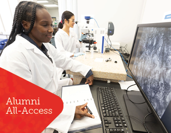 student in a lab coat studying a computer screen image