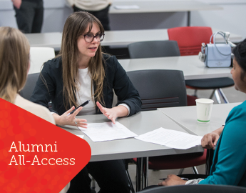 women discussing at desk with alumni all access tag